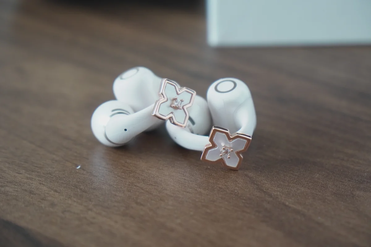 OpenDots 2に装着するローズゴールドの花型チャームと白色イヤホン本体のクローズアップ