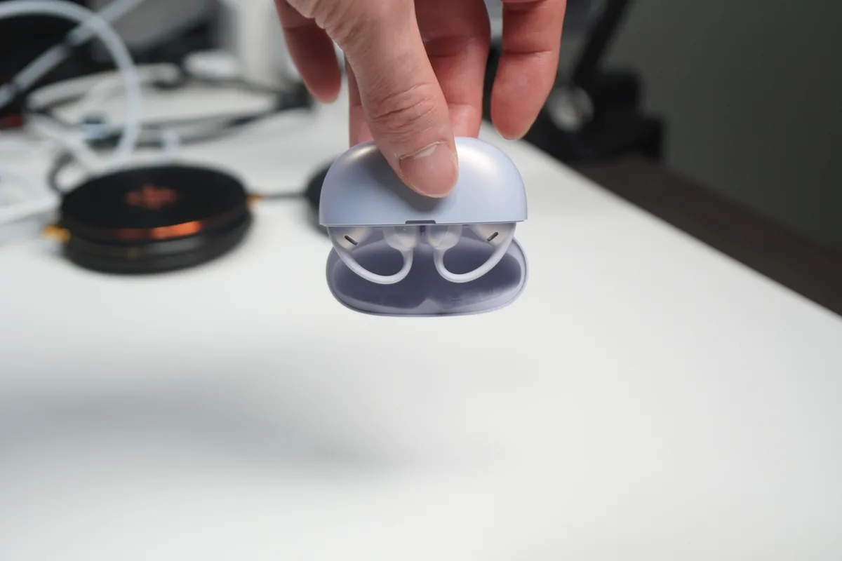 Shokz OpenDots Airの充電ケースを開けてイヤホンを収めた状態を手で持つ様子