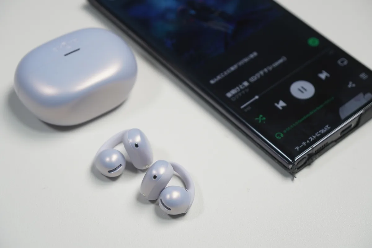 Shokz OpenDots Airのイヤホンと充電ケースをSpotify再生中のスマートフォンと並べた様子