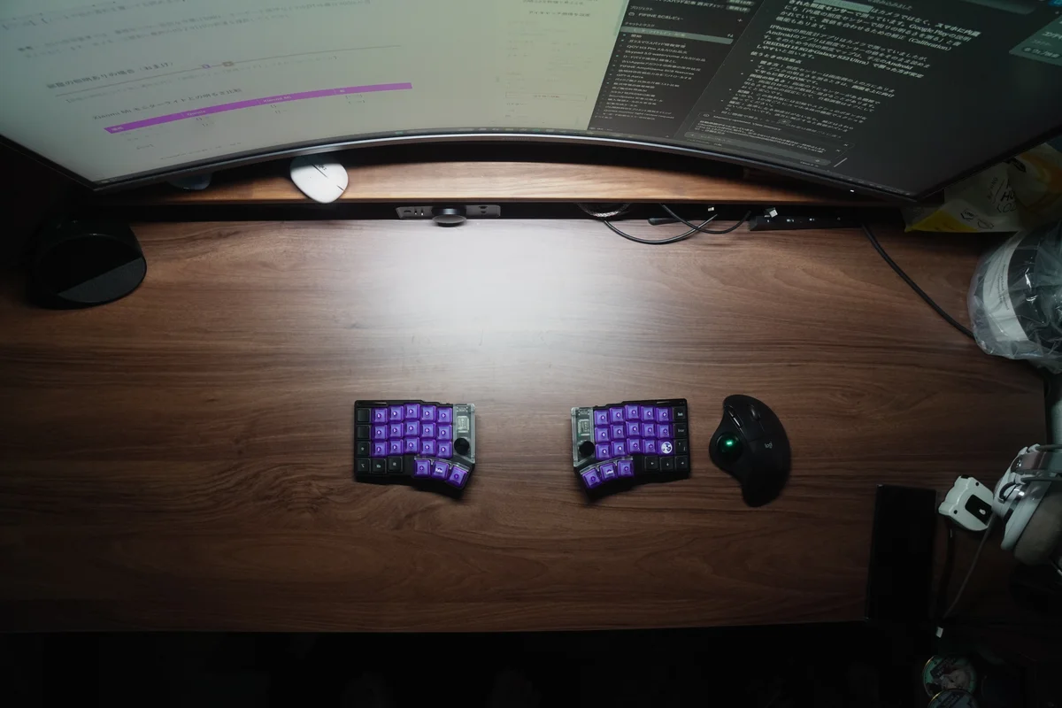 部屋の照明を消した夜にQuntis モニターライト Focus 40cmを点灯し、デスクのキーボード周りを照らした様子を真上から撮影した写真